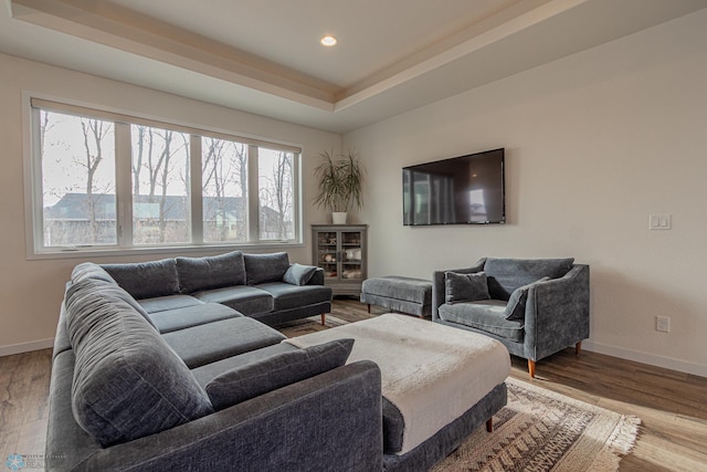 living room featuring a tray ceiling, recessed lighting, wood finished floors, and baseboards