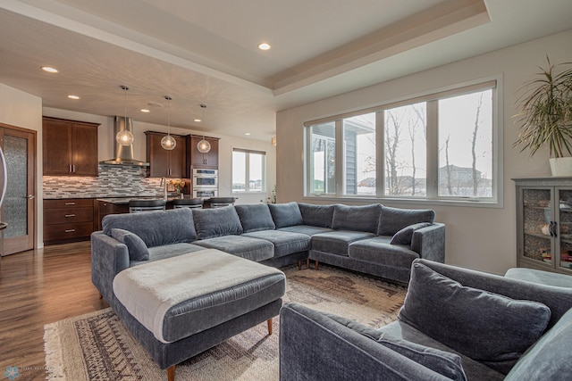 living area with recessed lighting, a raised ceiling, and dark wood-style flooring