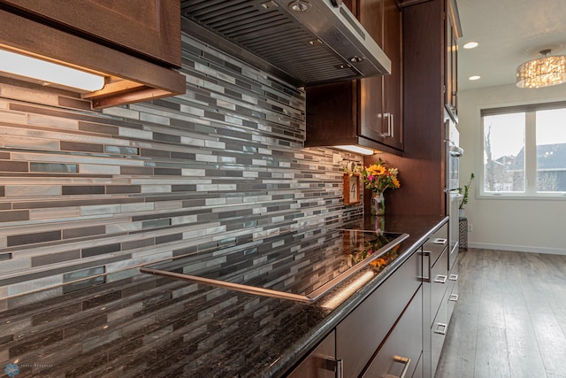 kitchen with backsplash, dark stone counters, ventilation hood, and black electric cooktop