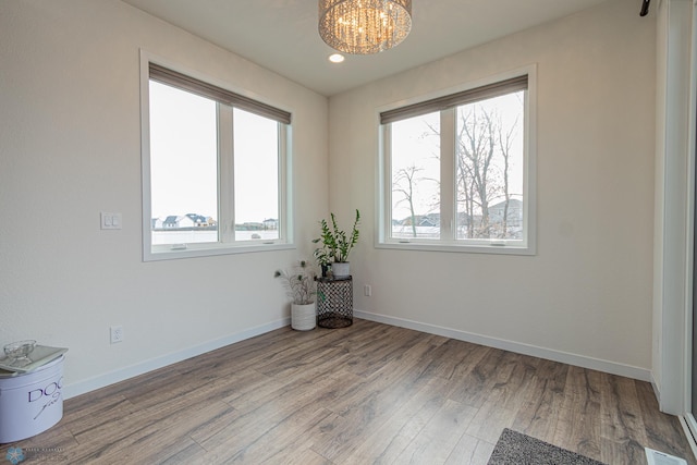 spare room with wood finished floors, visible vents, baseboards, recessed lighting, and a notable chandelier