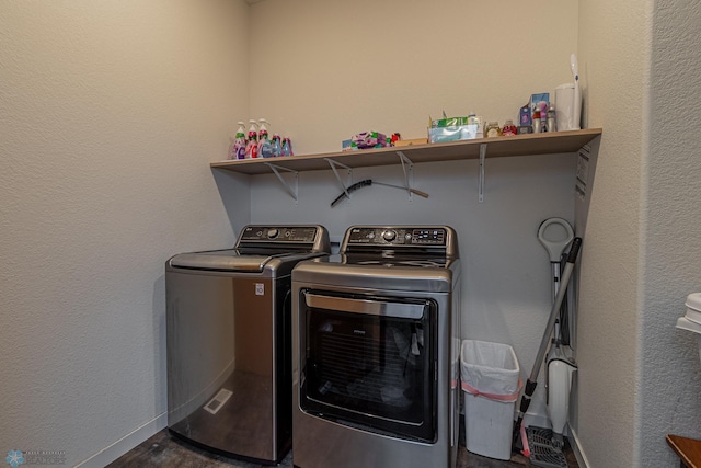 clothes washing area with laundry area, a textured wall, baseboards, and washer and clothes dryer