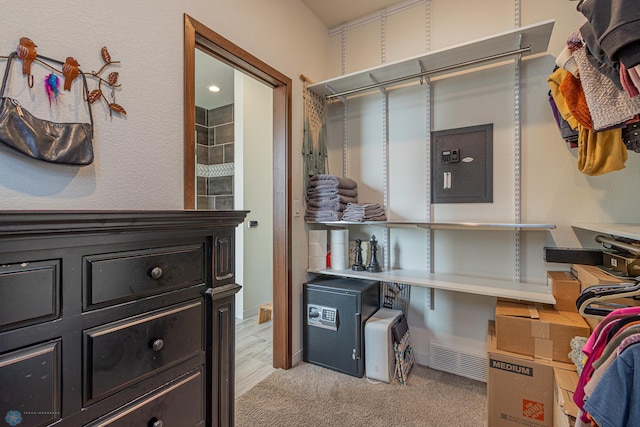 walk in closet with electric panel and light colored carpet