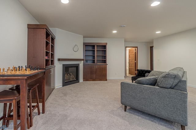 living room with a glass covered fireplace, recessed lighting, baseboards, and light carpet