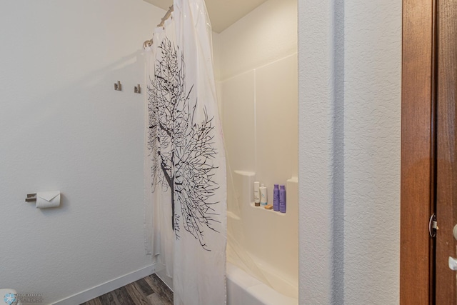 bathroom with shower / bathtub combination with curtain, baseboards, and wood finished floors