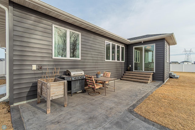 view of patio with area for grilling, entry steps, and fence