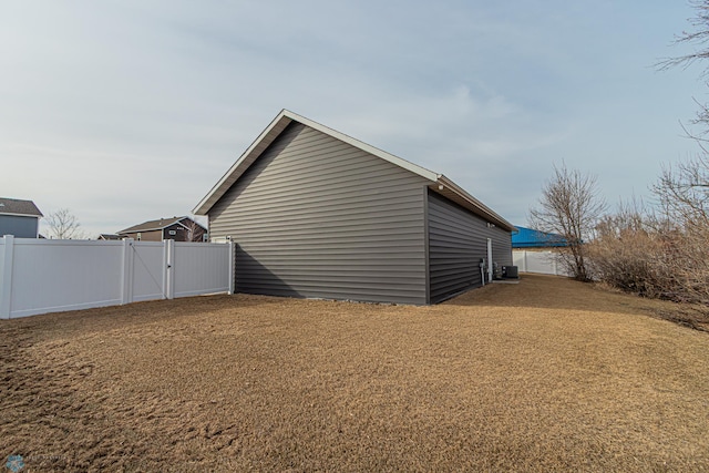 view of home's exterior with central AC unit, fence, and a gate