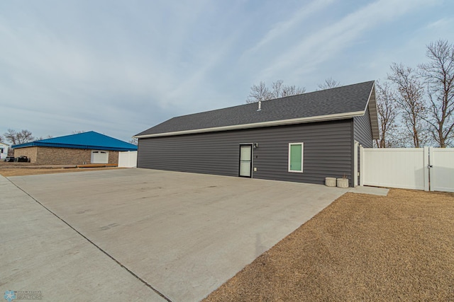 exterior space featuring a patio area, a gate, fence, and a shingled roof