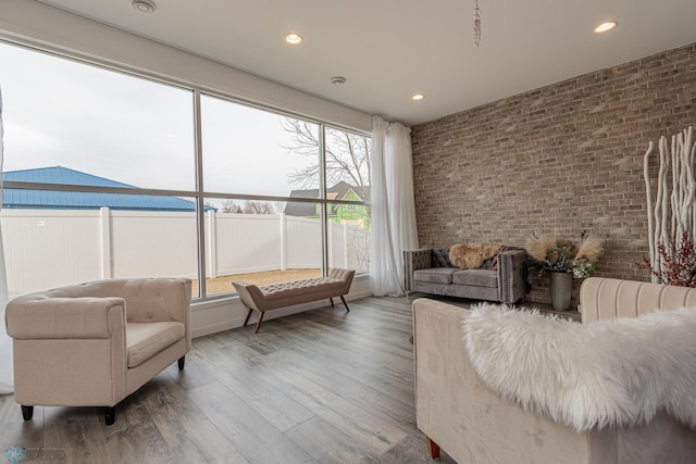 living area featuring recessed lighting, brick wall, and wood finished floors