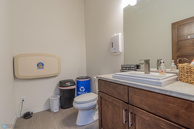 bathroom featuring toilet, vanity, and baseboards