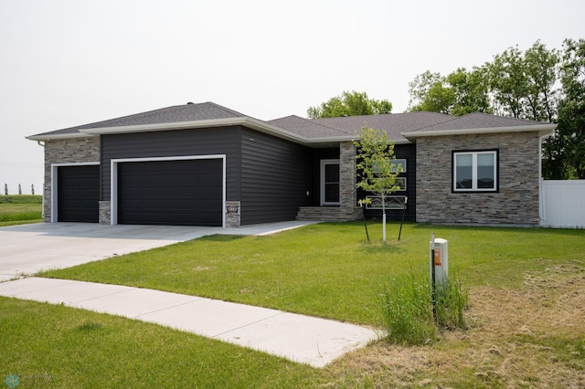 5881 31st St S, Fargo, ND 58104 - prairie-style home with a garage, stone siding, driveway, a front lawn, and roof with shingles