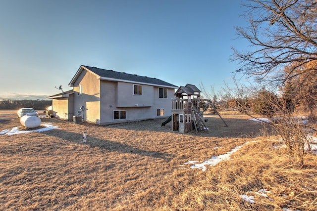 rear view of property with central air condition unit and a playground