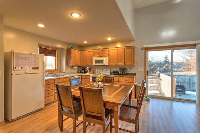 kitchen with white appliances, recessed lighting, light wood finished floors, and a sink