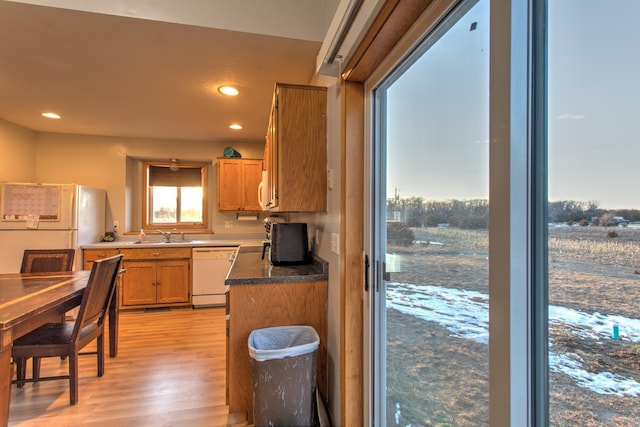 kitchen featuring a sink, dark countertops, recessed lighting, white appliances, and light wood finished floors