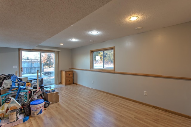 interior space with baseboards, a textured ceiling, a healthy amount of sunlight, and wood finished floors