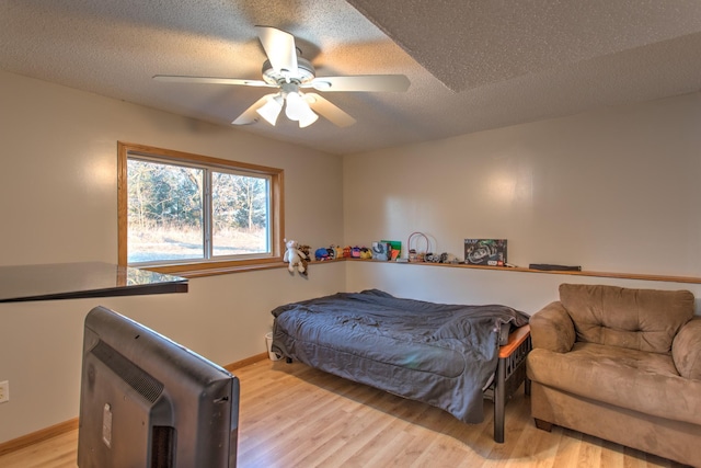 bedroom featuring baseboards, ceiling fan, a textured ceiling, and light wood-style floors