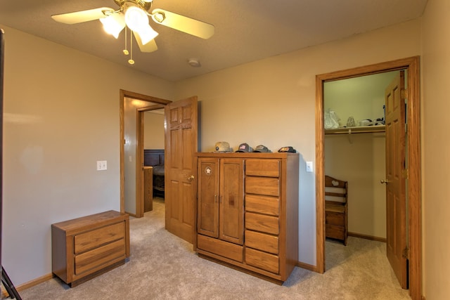 bedroom with a walk in closet, light colored carpet, a closet, and baseboards