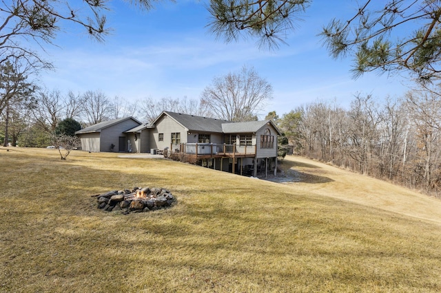 back of property featuring a lawn, an outdoor fire pit, and a deck