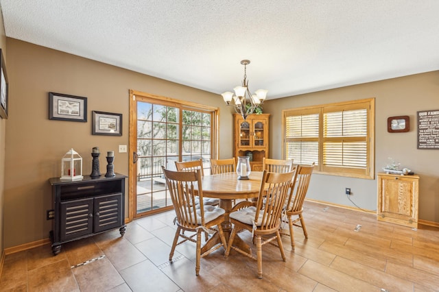 dining area with baseboards, a notable chandelier, and a textured ceiling