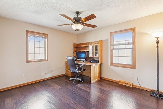 office space with visible vents, a ceiling fan, a healthy amount of sunlight, and dark wood-style flooring