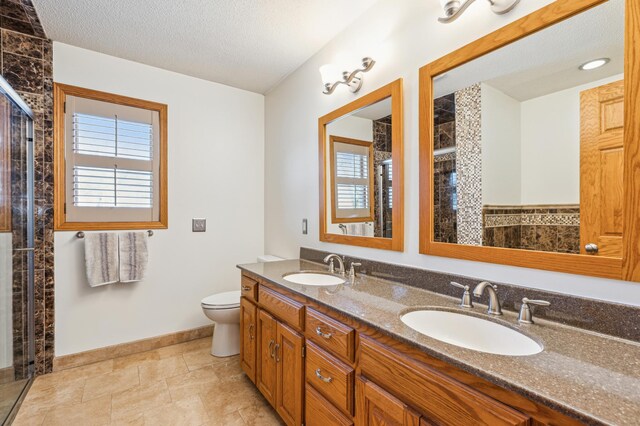 full bathroom with tiled shower, toilet, a textured ceiling, and a sink