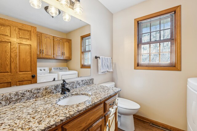 bathroom featuring vanity, visible vents, baseboards, toilet, and washer and clothes dryer