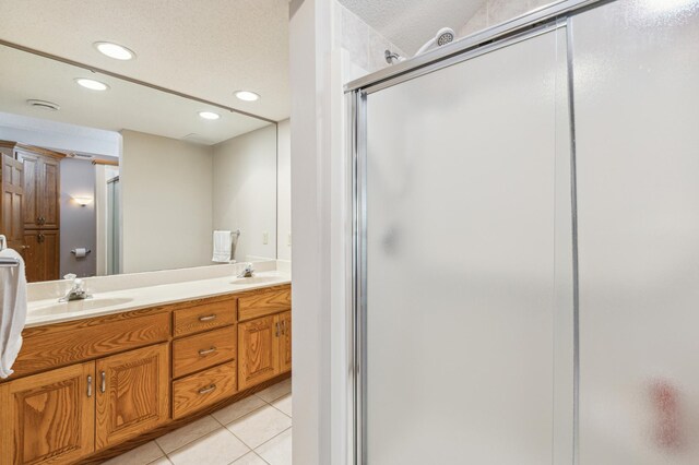 full bath featuring tile patterned floors, double vanity, a shower stall, and a sink