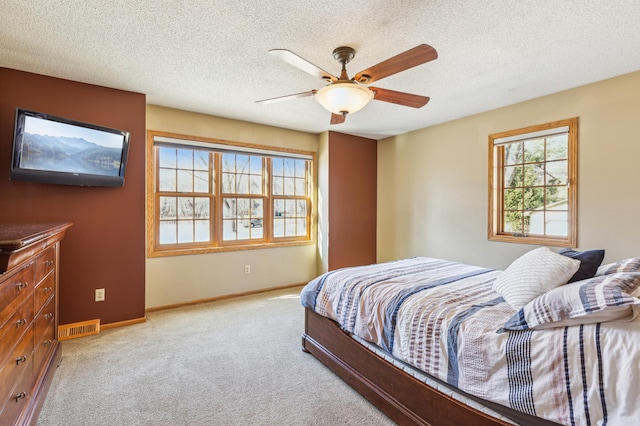 bedroom featuring visible vents, light colored carpet, a textured ceiling, and baseboards