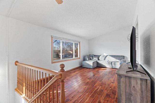 interior space featuring vaulted ceiling, an upstairs landing, and dark wood-style floors