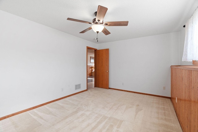 unfurnished room featuring light carpet, visible vents, baseboards, and a ceiling fan