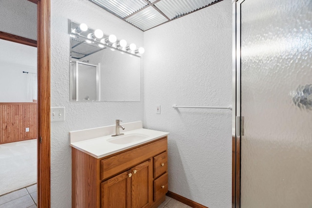 full bath featuring tile patterned floors, vanity, a shower stall, and a textured wall