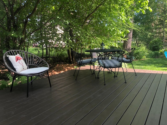 wooden terrace featuring a lawn and outdoor dining space