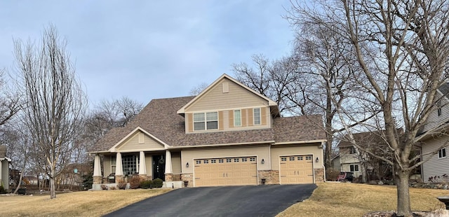 view of front of house with stone siding, driveway, a front lawn, and a garage