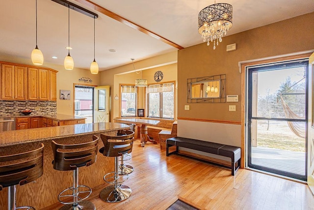 kitchen with decorative backsplash, a healthy amount of sunlight, light wood-style flooring, and brown cabinetry