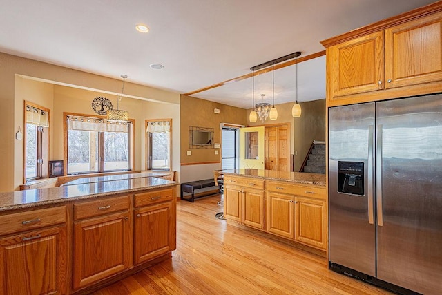 kitchen with brown cabinets, hanging light fixtures, stainless steel refrigerator with ice dispenser, and light wood finished floors