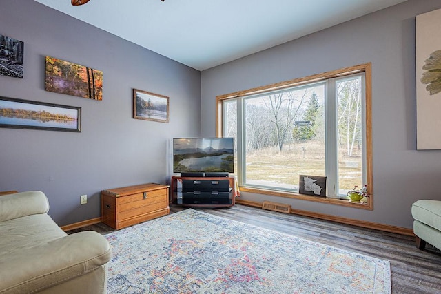 living room with wood finished floors, visible vents, and baseboards