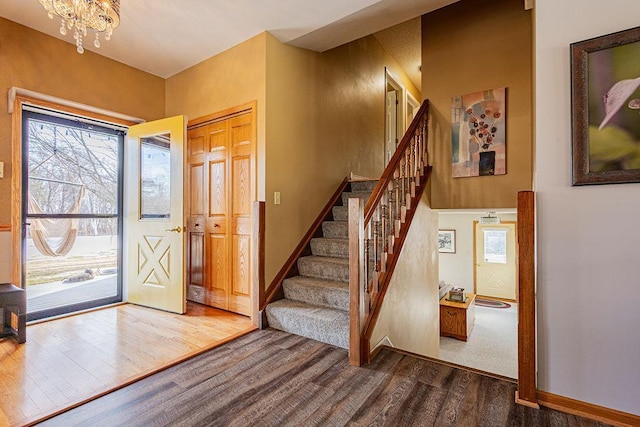 entrance foyer featuring a healthy amount of sunlight, wood finished floors, stairs, and an inviting chandelier