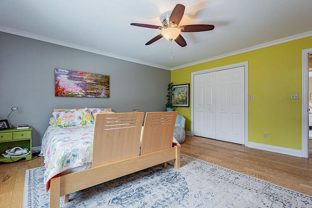 bedroom with crown molding, wood finished floors, baseboards, and a closet