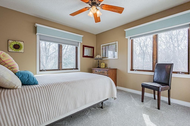 carpeted bedroom featuring a ceiling fan, baseboards, and a textured ceiling