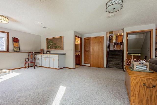 interior space featuring stairway, light carpet, a textured ceiling, and baseboards