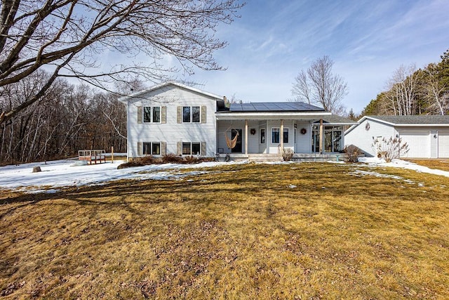 tri-level home featuring covered porch, solar panels, an attached garage, and a yard