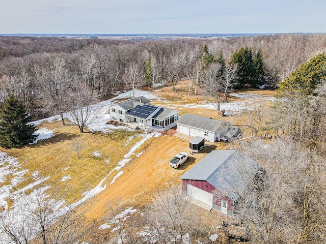 snowy aerial view featuring a wooded view