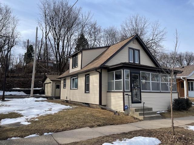 view of front facade featuring an outbuilding, entry steps, a shed, a sunroom, and a garage