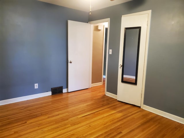 empty room with visible vents, light wood-style floors, and baseboards