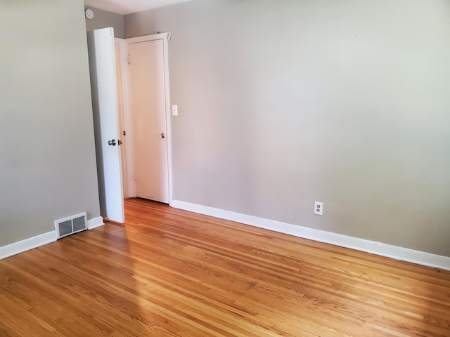 empty room with visible vents, light wood-type flooring, and baseboards