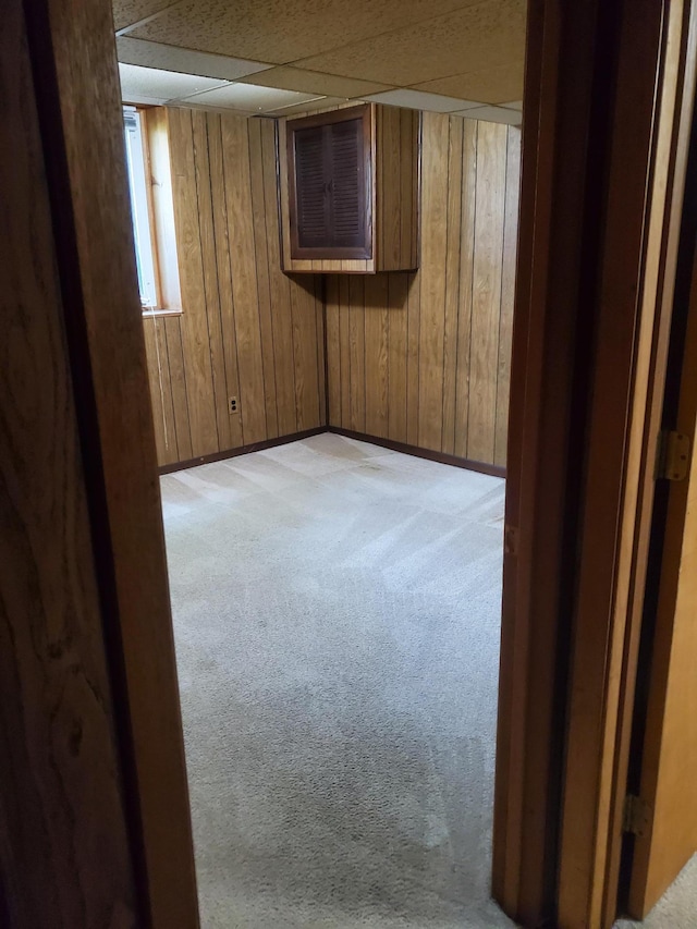 spare room featuring wooden walls, a paneled ceiling, baseboards, and light carpet