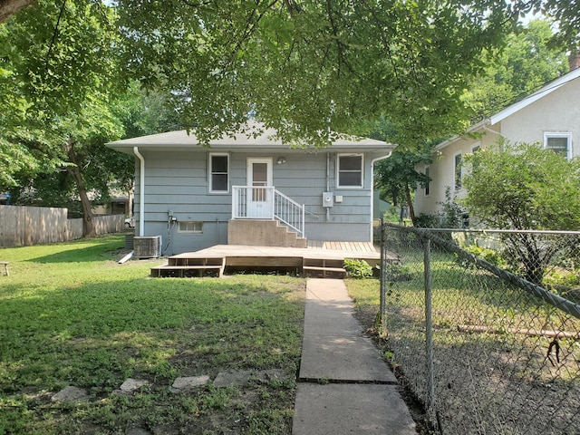 view of front of house with a deck, a front yard, a fenced backyard, and central AC