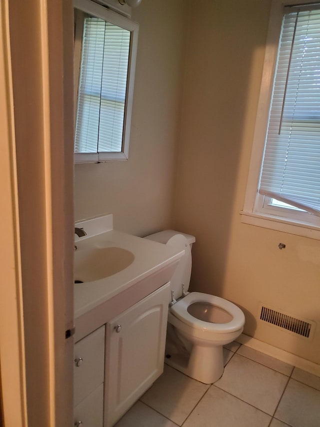 half bathroom with tile patterned flooring, toilet, vanity, and visible vents