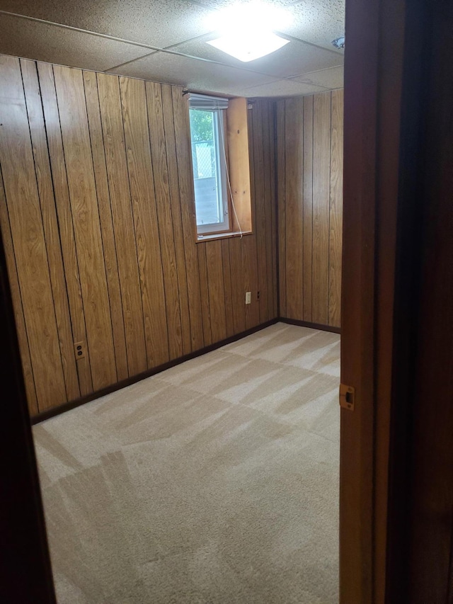 unfurnished room with baseboards, wood walls, and light carpet