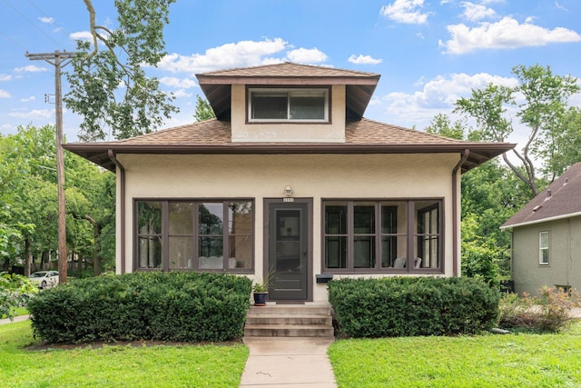 bungalow featuring stucco siding, a shingled roof, and a front yard