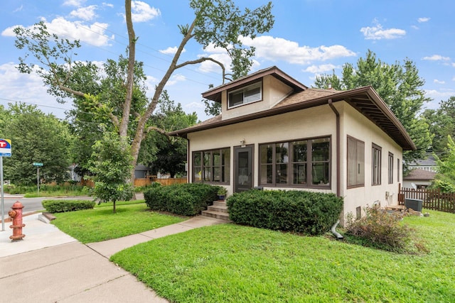 view of front facade with stucco siding, a front yard, and fence